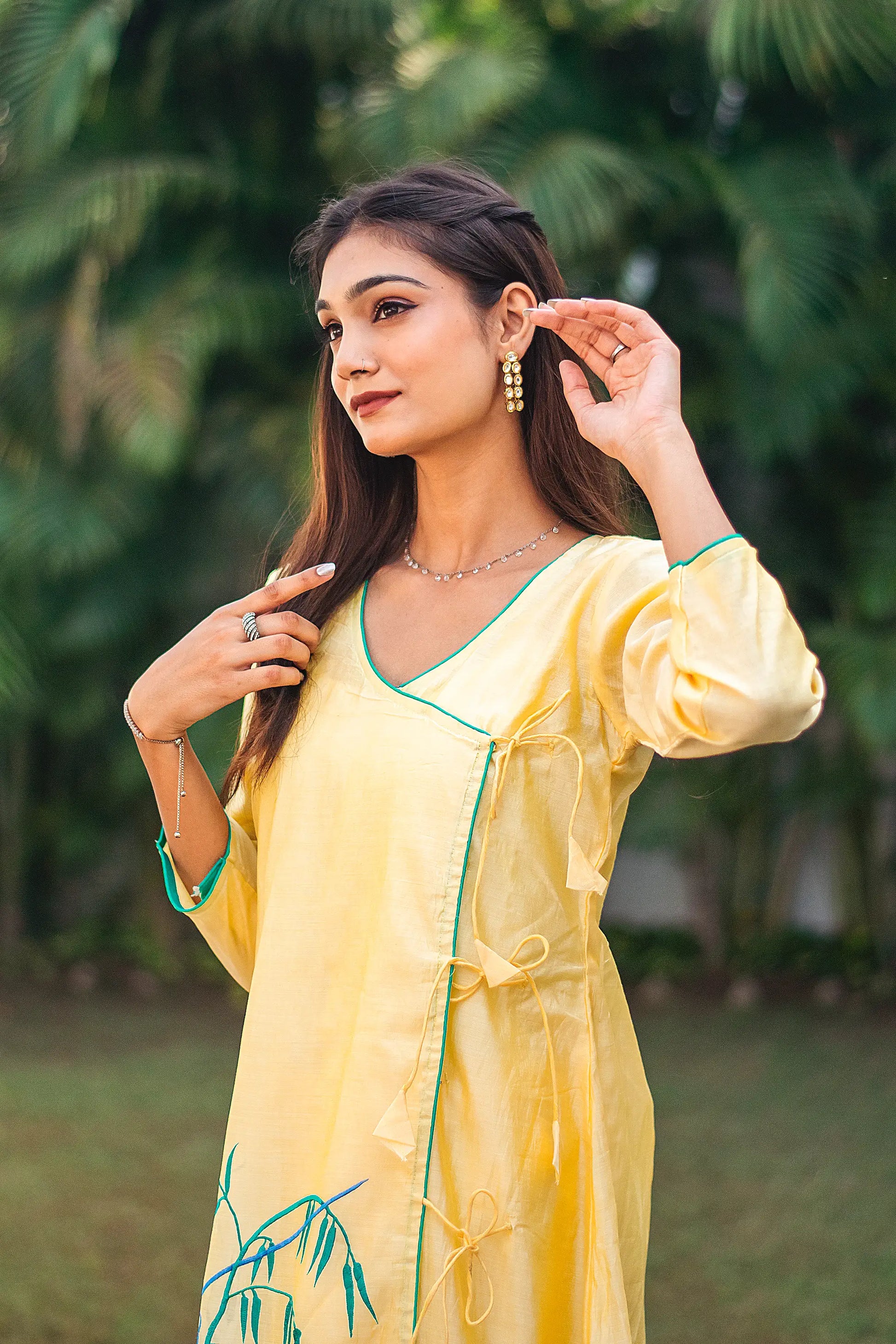 Side view of an Indian model in a yellow angrakha kurta with delicate resham floral embroidery.