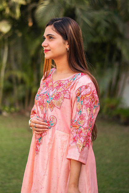 Side view of an Indian model in a peach Chanderi kurta with floral resham embroidery and pink sequins.