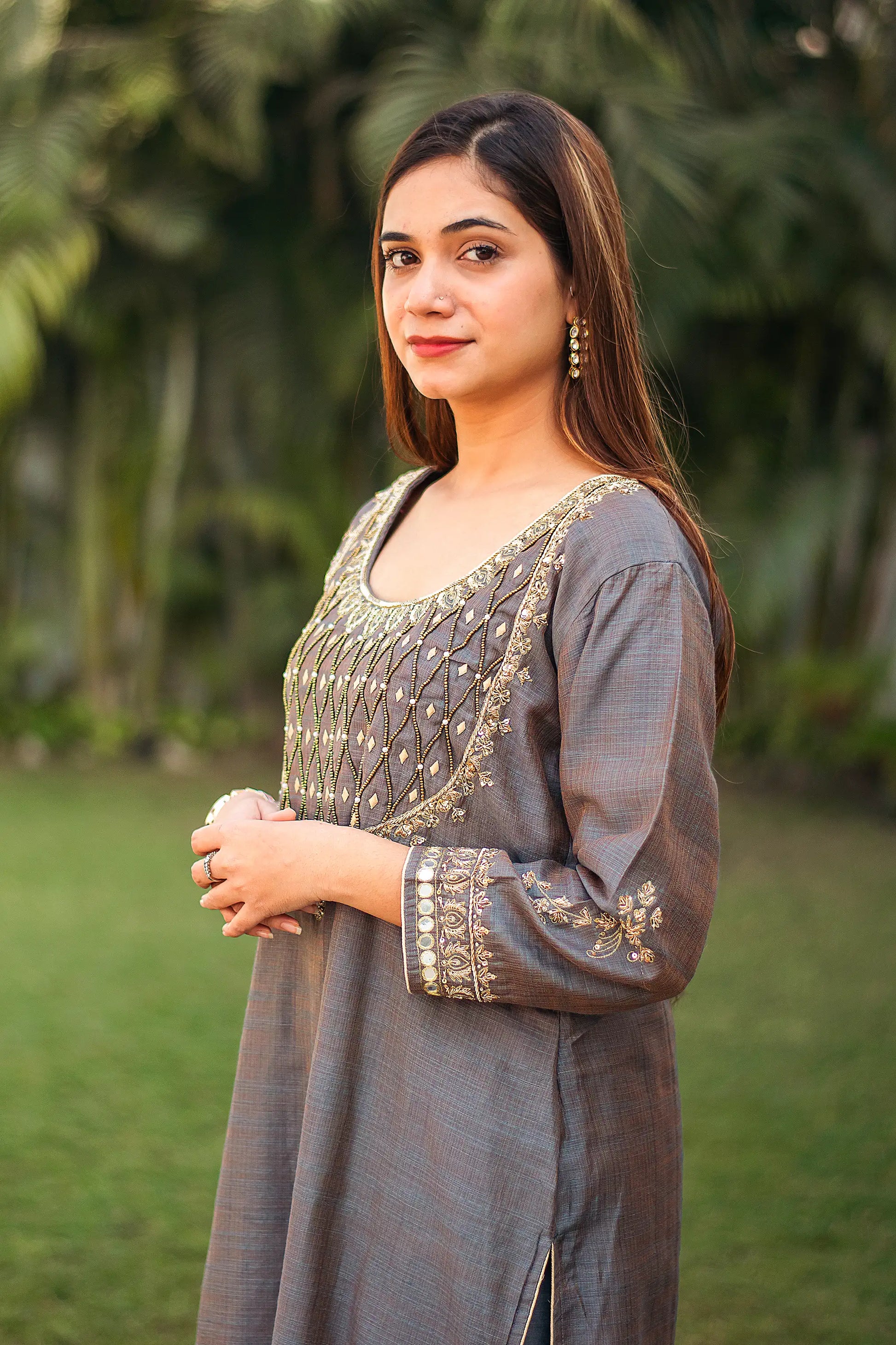 Side view of an Indian model in a grey silk kurta with golden zardozi work.