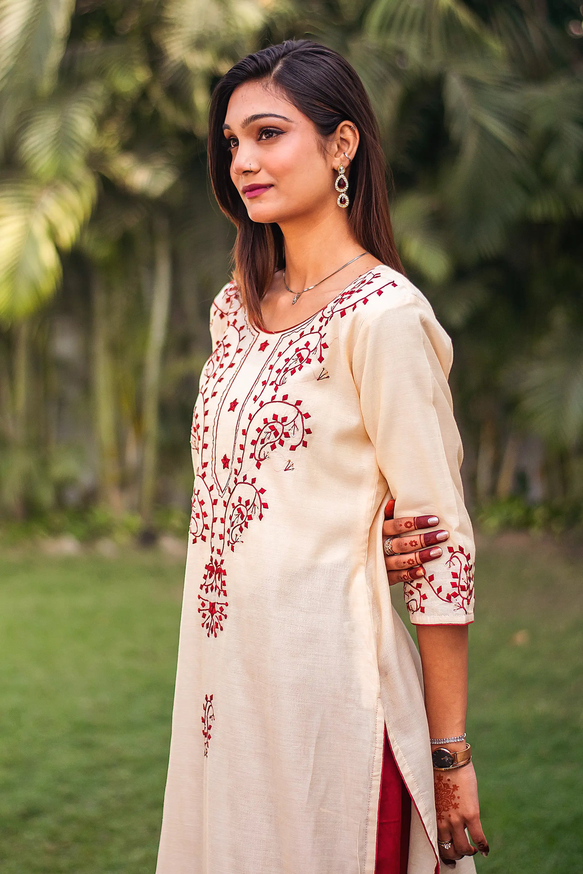 Side view of an Indian model in a beige chanderi kurta with maroon paisley motifs and geometric applique work.