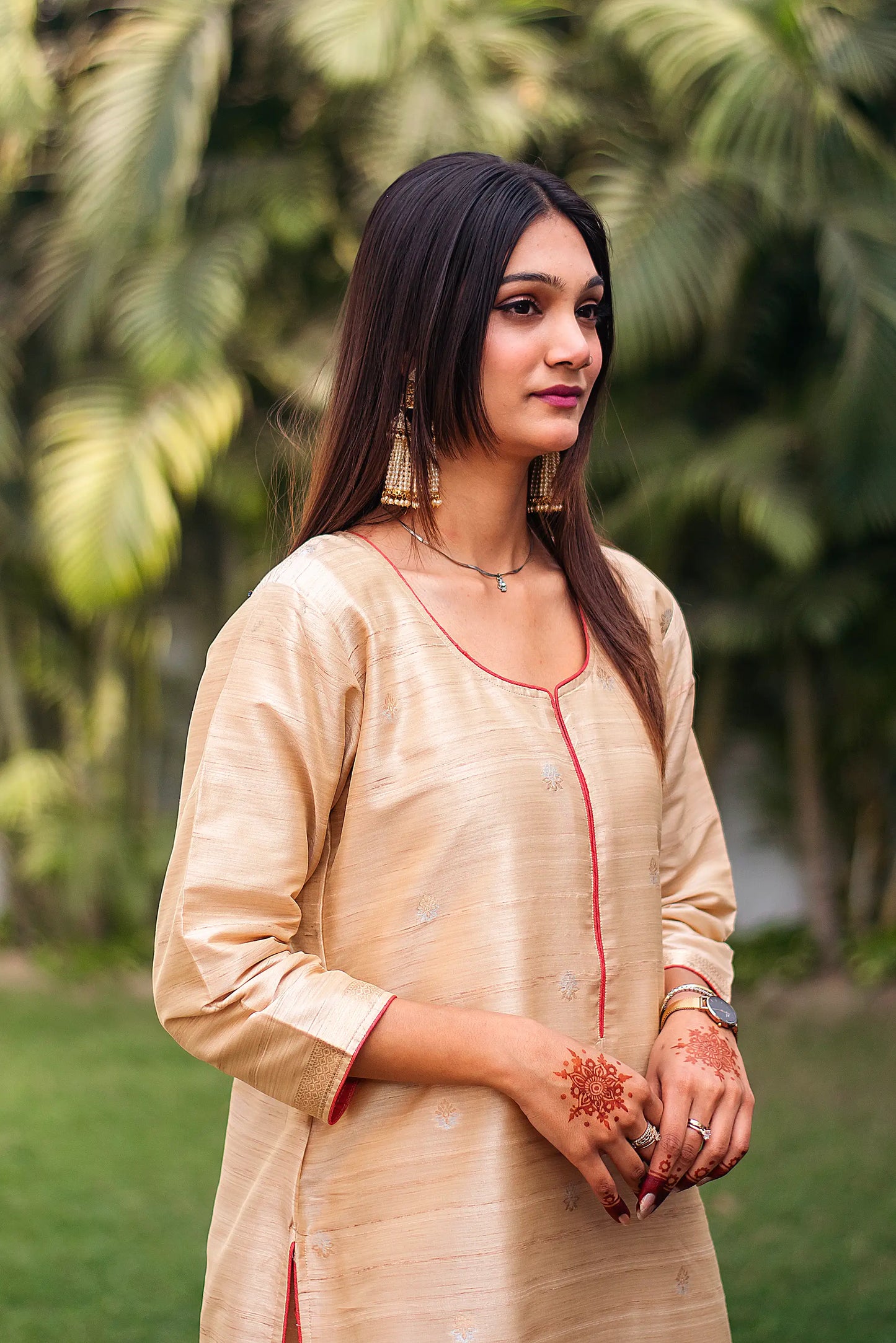  Indian model posing sideways in a  beige silk kurta.