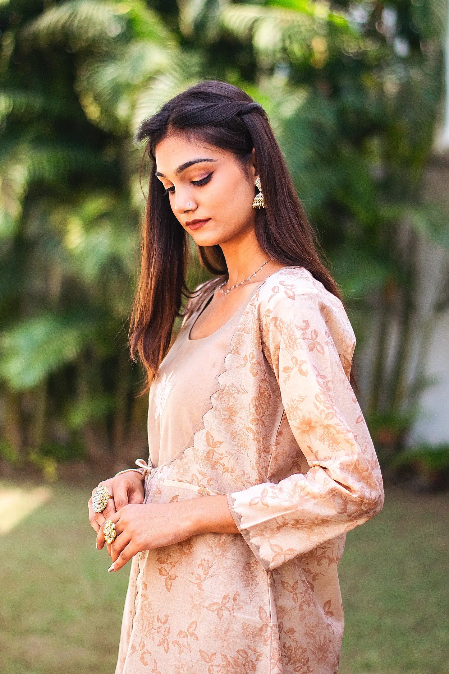 Upper half left side view of a model wearing the beige floral print kurta set, featuring a beige floral print chanderi angrakha, matching palazzo