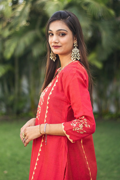  Side view of an Indian model in a red jute silk kalidar kurta with beige applique work. 