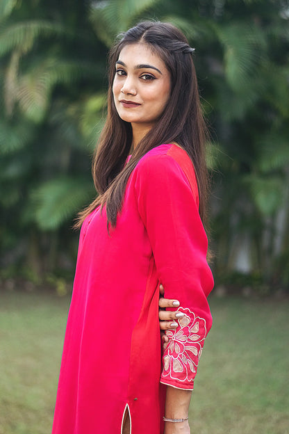 Side pose of an Indian model wearing a red organza kurta with opulent gold cutwork along the cuff is visible.