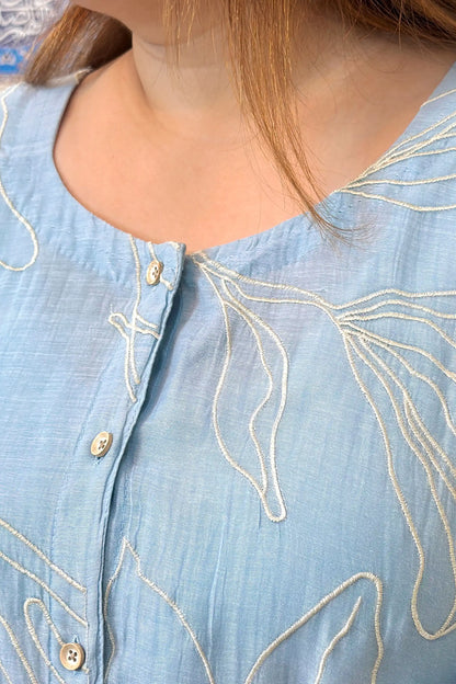Close-up of the button placket on the blue chanderi kurta, showing white floral resham embroidery detail.