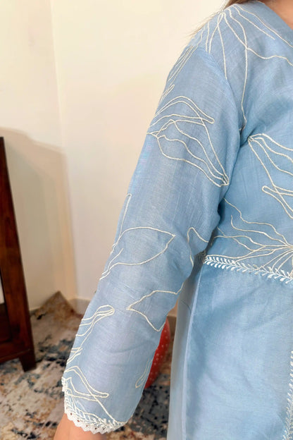 Close-up of the sleeve on the blue chanderi kurta, showing white floral resham embroidery and lace trim at the cuff.