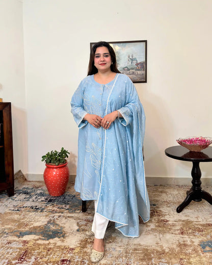 Front view of the blue chanderi A-line kurta and dupatta with white floral resham embroidery, dupatta on, worn with off-white trousers.
