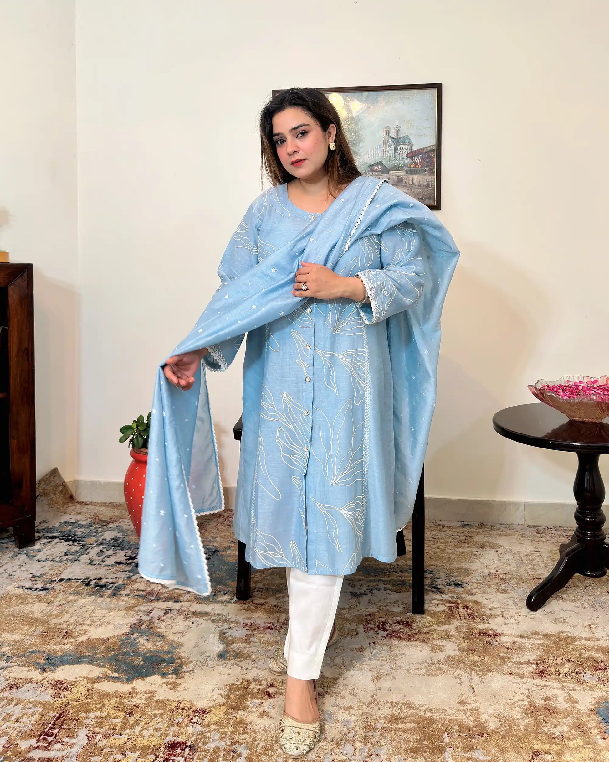 Front view of the blue chanderi A-line kurta and dupatta with white floral resham embroidery, dupatta on, worn with off-white trousers.