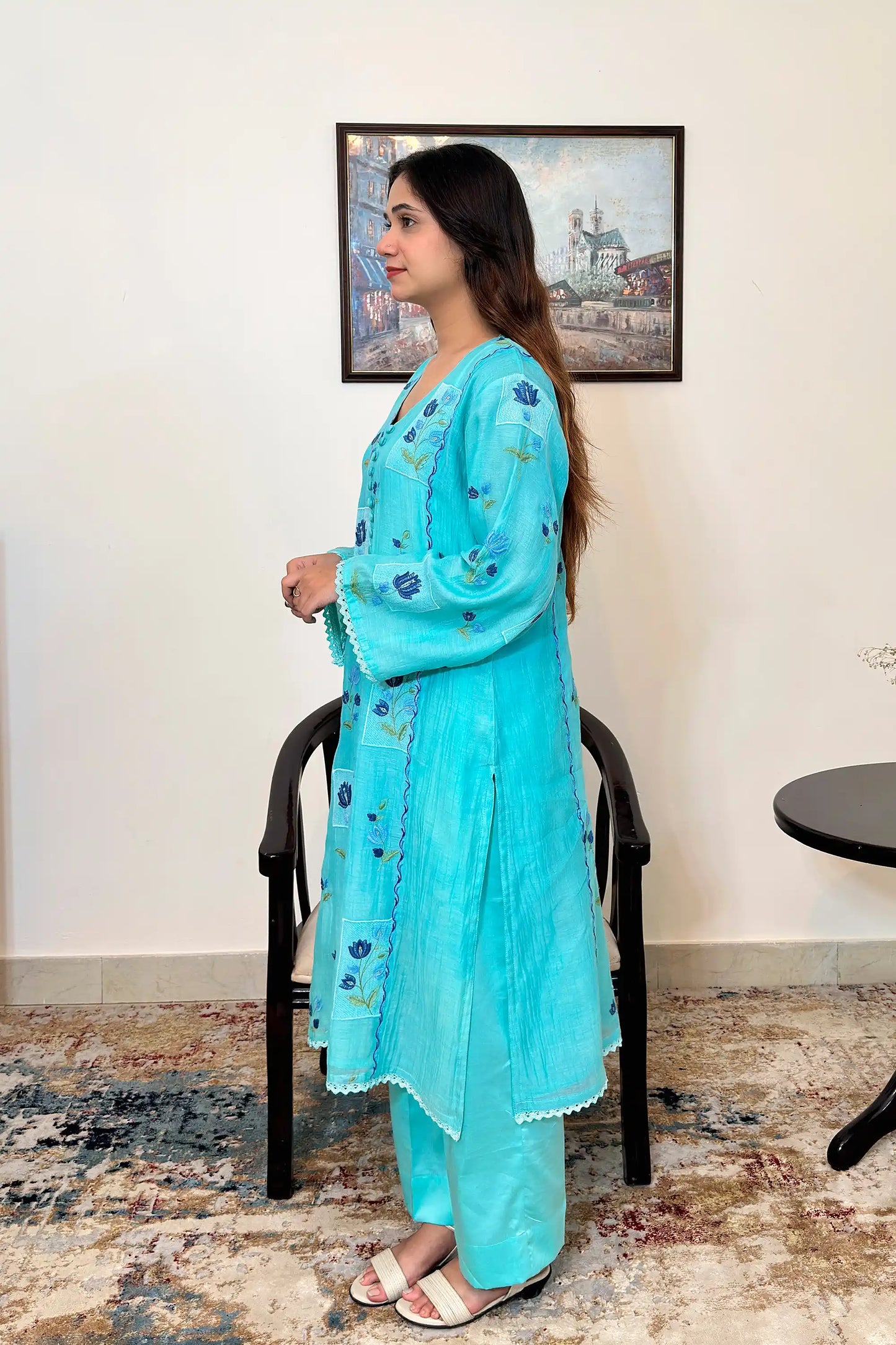 Side view of an aqua-blue chanderi kalidar kurta, featuring blue floral resham embroidery and a button placket, paired with aqua-blue trousers.