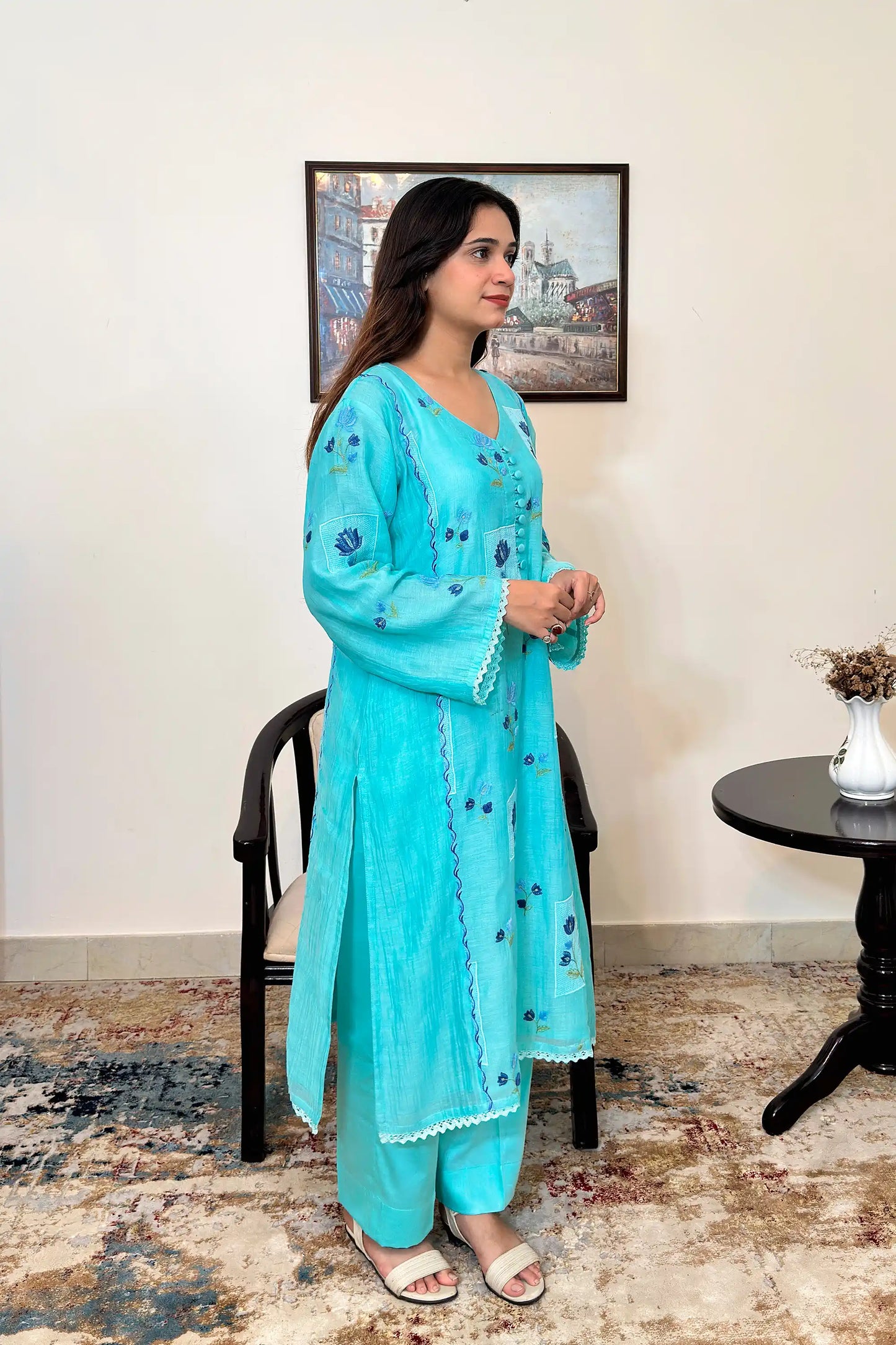 Side view of an aqua-blue chanderi kalidar kurta, featuring blue floral resham embroidery and a button placket, paired with aqua-blue trousers.