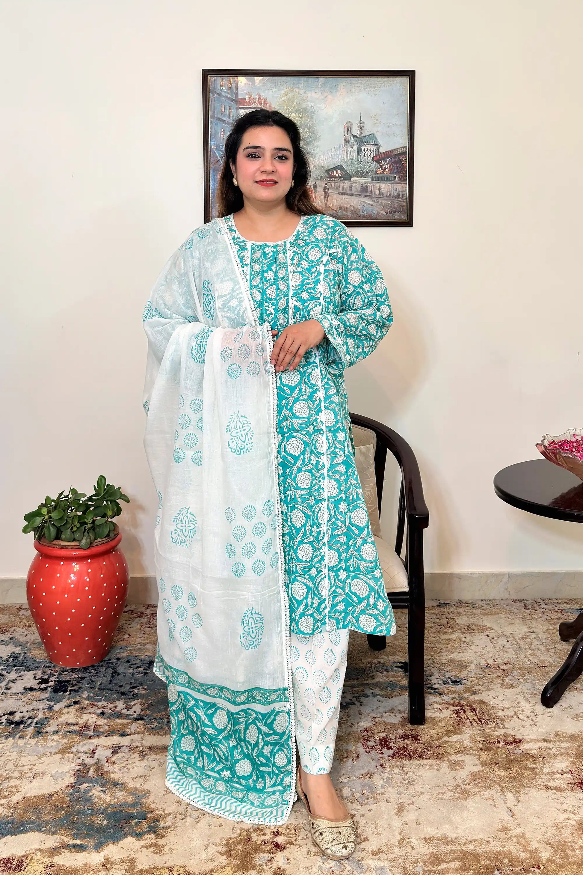Front view of a woman wearing a turquoise-green mulmul cotton kalidar kurta with an all over white floral print, paired with an off-white printed dupatta with applique work and off-white printed trousers.