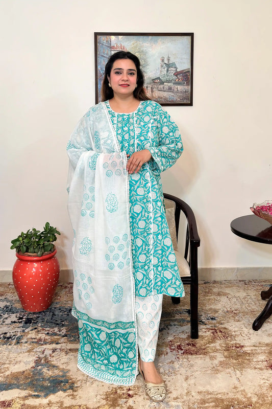 Front view of a woman wearing a turquoise-green mulmul cotton kalidar kurta with an all over white floral print, paired with an off-white printed dupatta with applique work and off-white printed trousers.