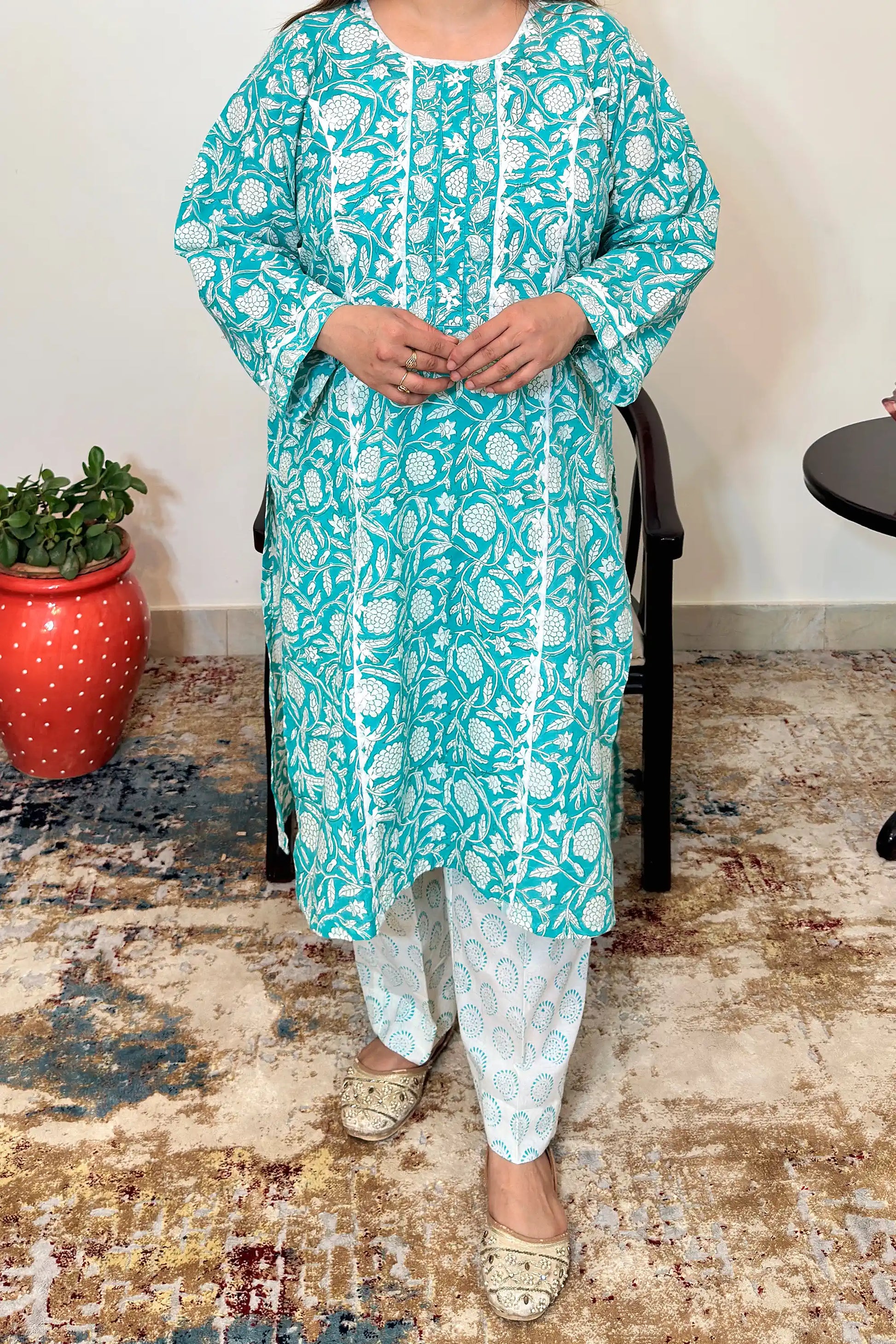 Front view of the turquoise-green mulmul cotton kalidar kurta with white floral print and applique work, worn over off-white printed trousers.