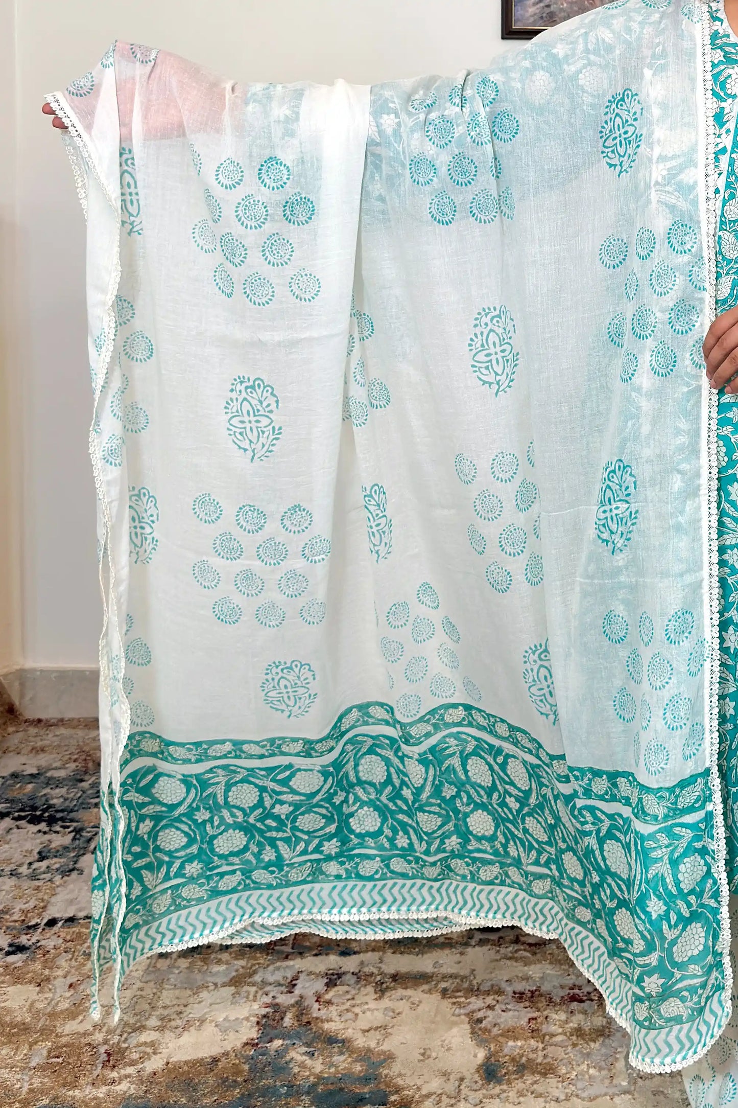 Close-up of the off-white mulmul dupatta with turquoise floral print and a scalloped lace-trimmed border.