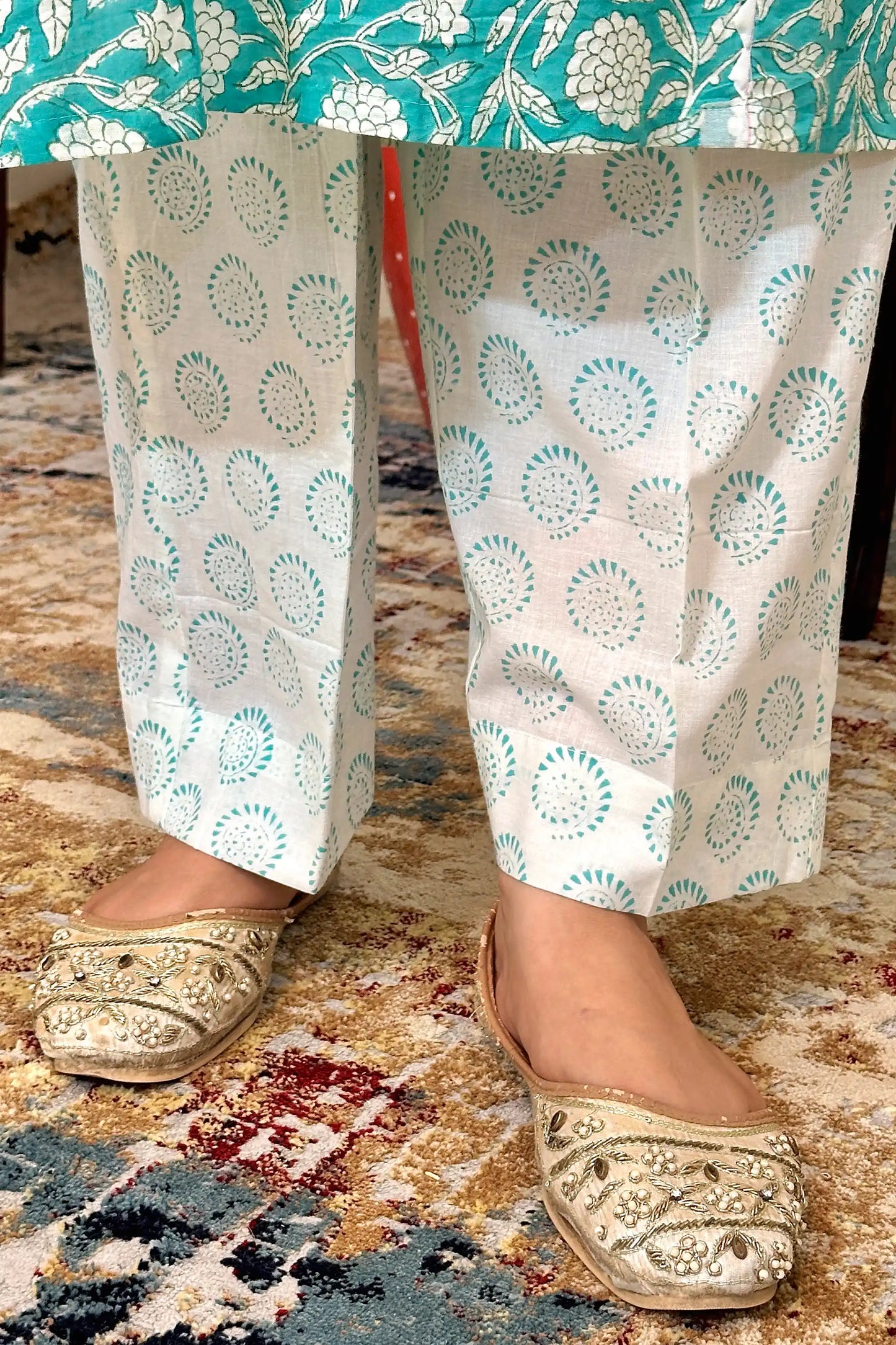 Close-up of the off-white printed trousers with turquoise circular motifs, shown at the hem.