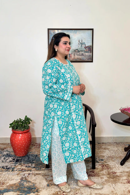 Side view of a woman wearing the turquoise-green printed kalidar kurta, paired with off-white printed trousers.