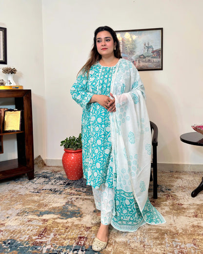 Front view of a woman standing, wearing the turquoise-green printed applique work kalidar kurta with off-white printed dupatta and trousers.