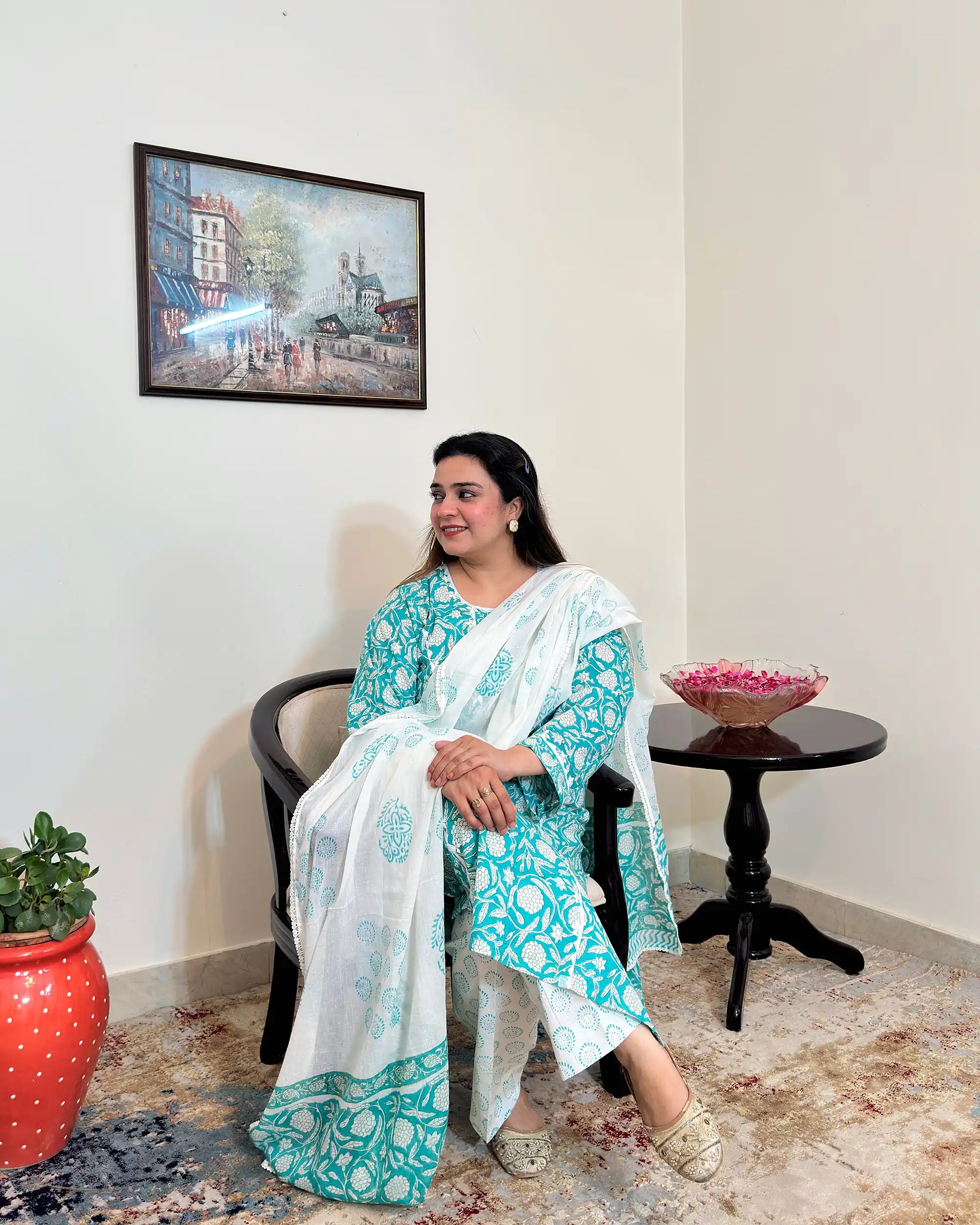 Front view of a woman posing, wearing the turquoise-green printed applique work kalidar kurta with off-white printed dupatta and trousers.