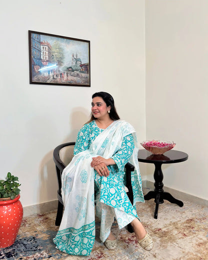 Front view of a woman posing, wearing the turquoise-green printed applique work kalidar kurta with off-white printed dupatta and trousers.