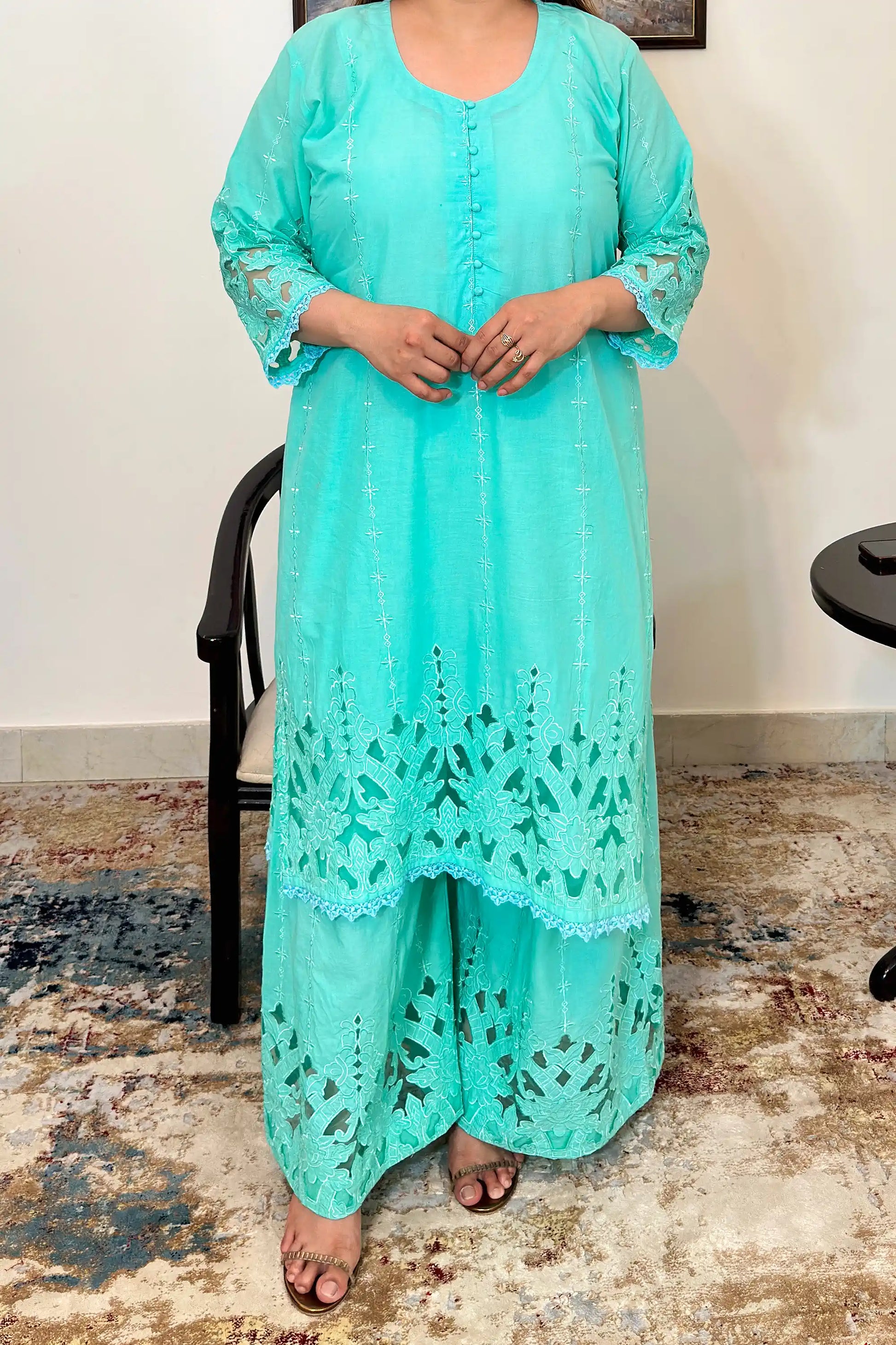 Close-up front view of the aqua-green cotton straight kurta showing the button placket and floral cutwork embroidery on the hem.