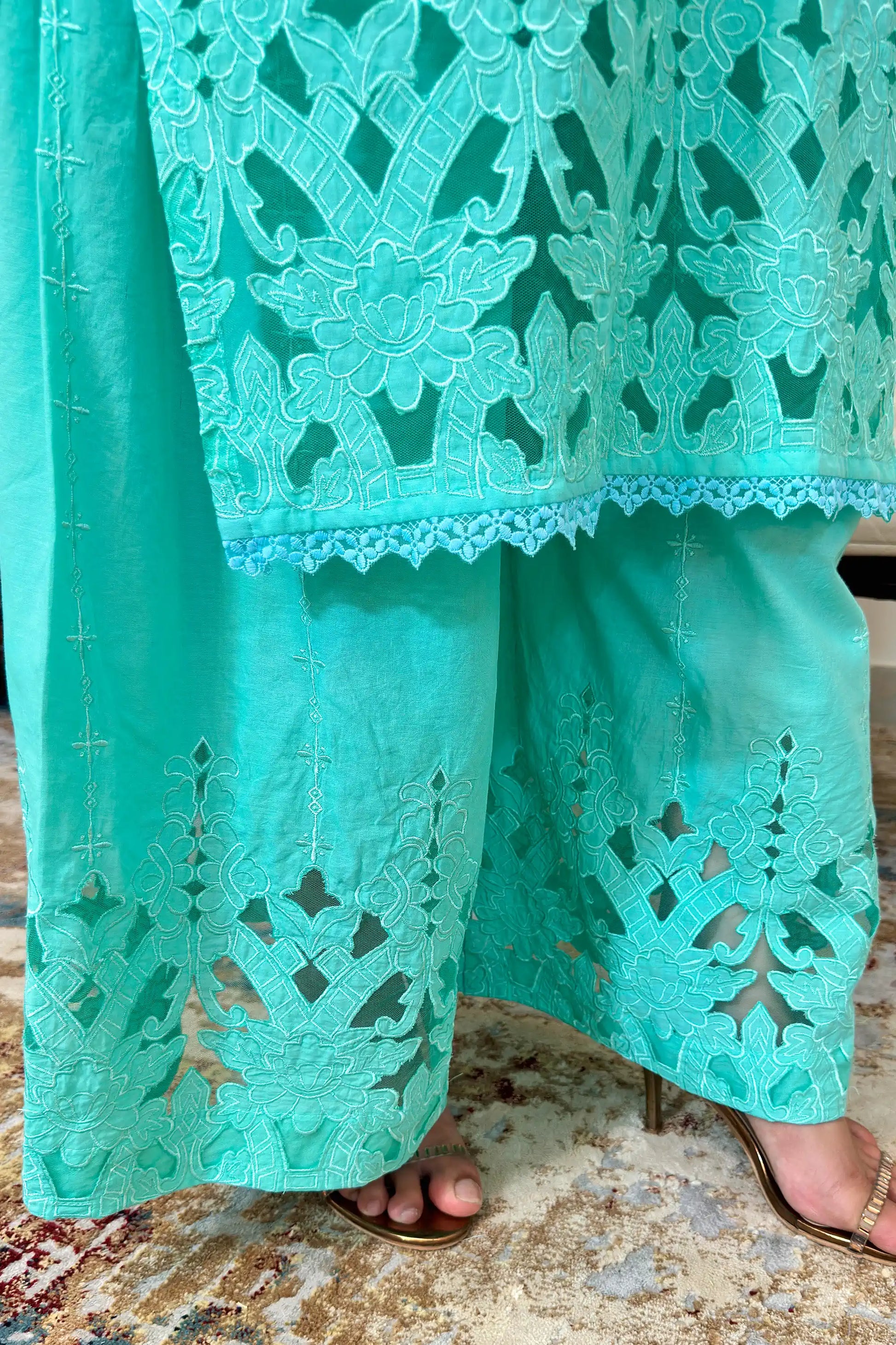 Close-up of the hem of the aqua-green cotton straight kurta and matching palazzo showing floral cutwork embroidery.