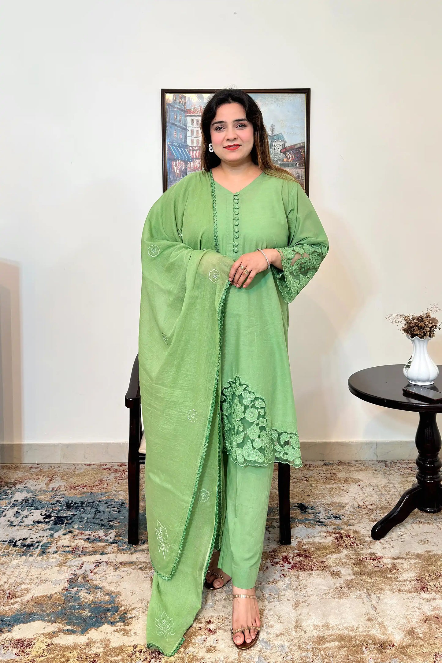 Green cotton straight kurta with a V-neck and button placket, floral cutwork sleeve cuffs and hem, paired with a green dupatta with scattered floral motifs and a scalloped edge, and green trousers.