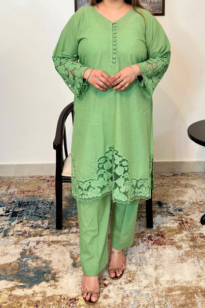 Green cotton straight kurta with a V-neck, fabric-covered button placket, floral cutwork sleeve cuffs and hem, paired with green trousers.