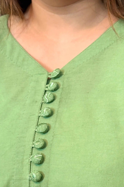 Close-up of the V-neckline with a row of fabric-covered buttons in matching green fabric.
