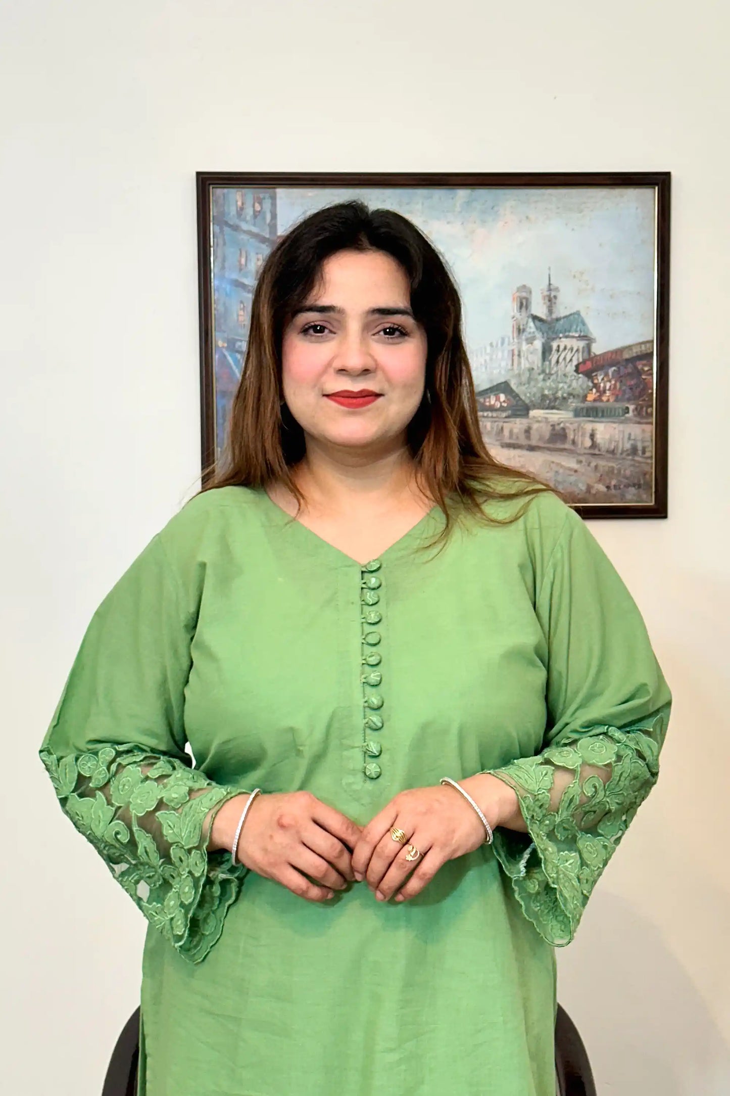 Upper half of a green cotton straight kurta with a V-neck, fabric-covered button placket, and floral cutwork sleeve cuff.