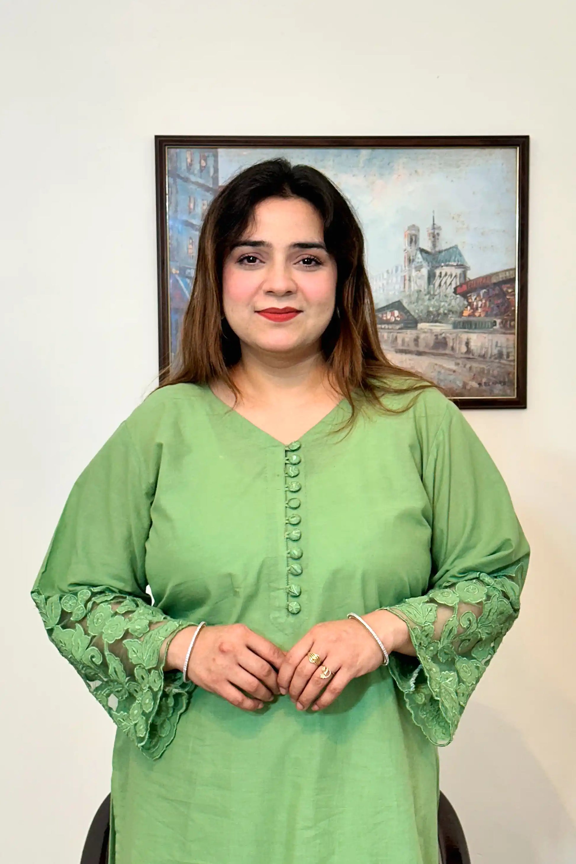 Upper half of a green cotton straight kurta with a V-neck, fabric-covered button placket, and floral cutwork sleeve cuff.