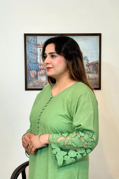 Model shown in profile in a green cotton straight kurta, showing the button placket and floral cutwork sleeve cuff.
