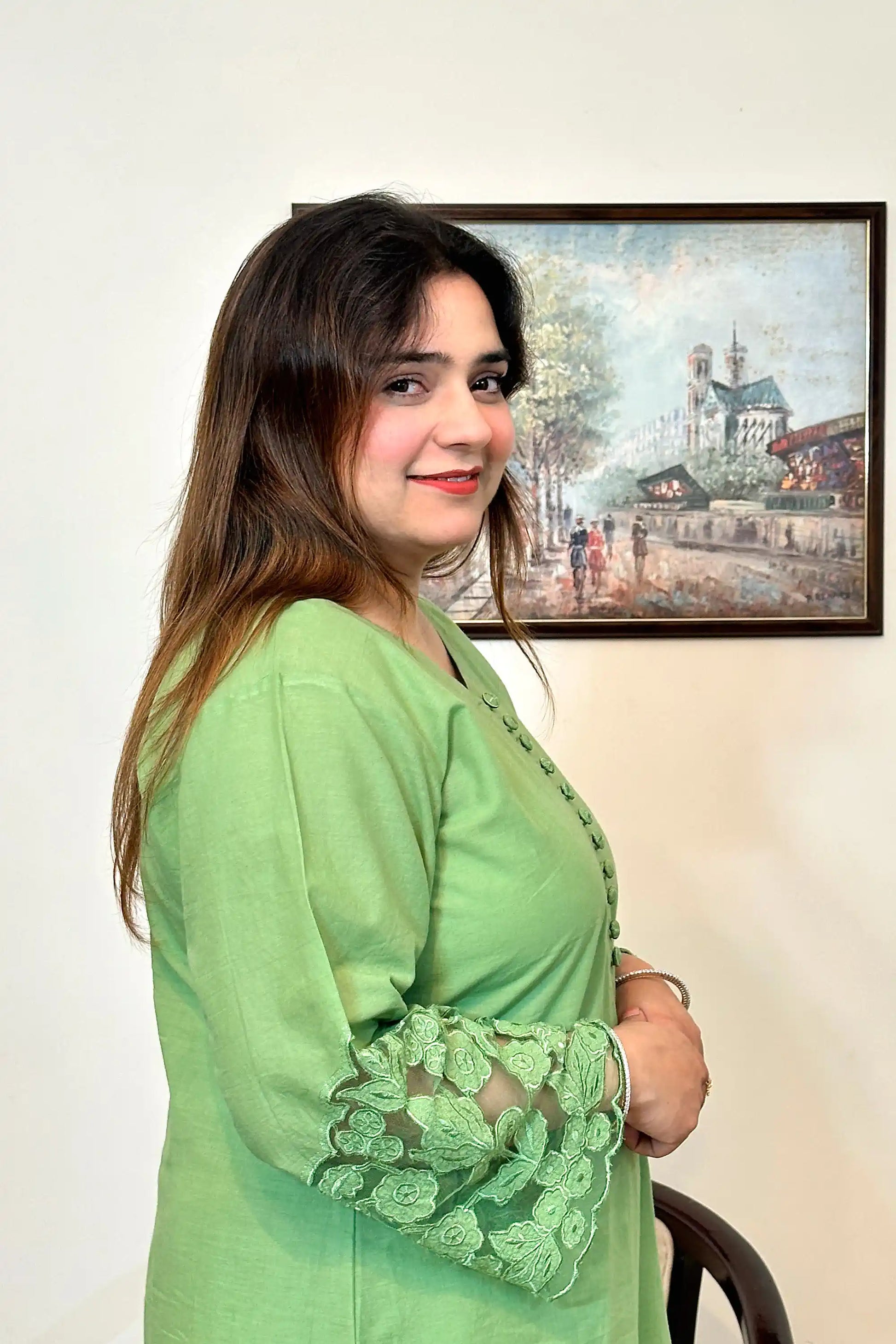 Side view of the model wearing a green cotton straight kurta, showing the fabric-covered button placket and floral cutwork sleeve cuff.