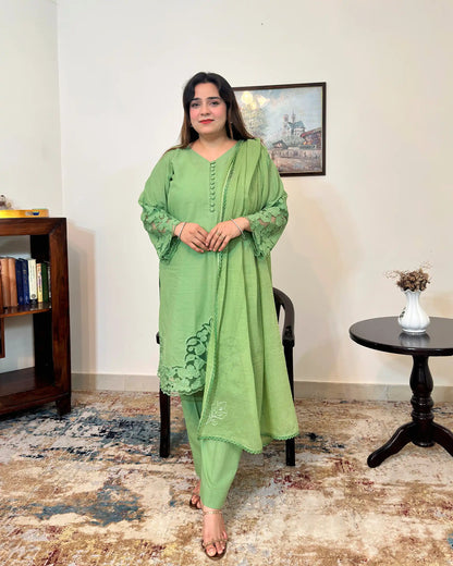 Green cotton straight kurta with a V-neck and button placket, floral cutwork sleeve cuffs and hem, paired with a green dupatta with scattered floral motifs and a scalloped edge, and green trousers.