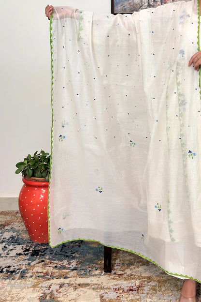 Close-up of the off-white chanderi dupatta held open, showing scattered dot embroidery across the fabric and a green scalloped appliqué border along the edge.