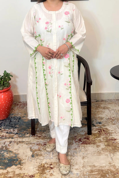 Close-up front view of the off-white chanderi A-line kurta showing pink floral embroidery and green applique vine trim along the front panel, dupatta off.