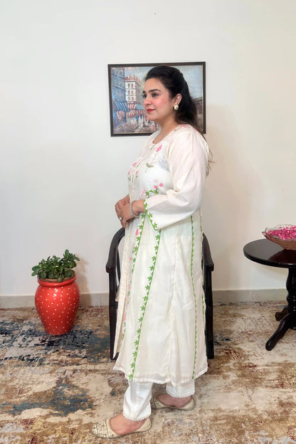 Side view of the off-white chanderi A-line kurta with pink floral embroidery and green applique vine, paired with off-white trousers, dupatta off.