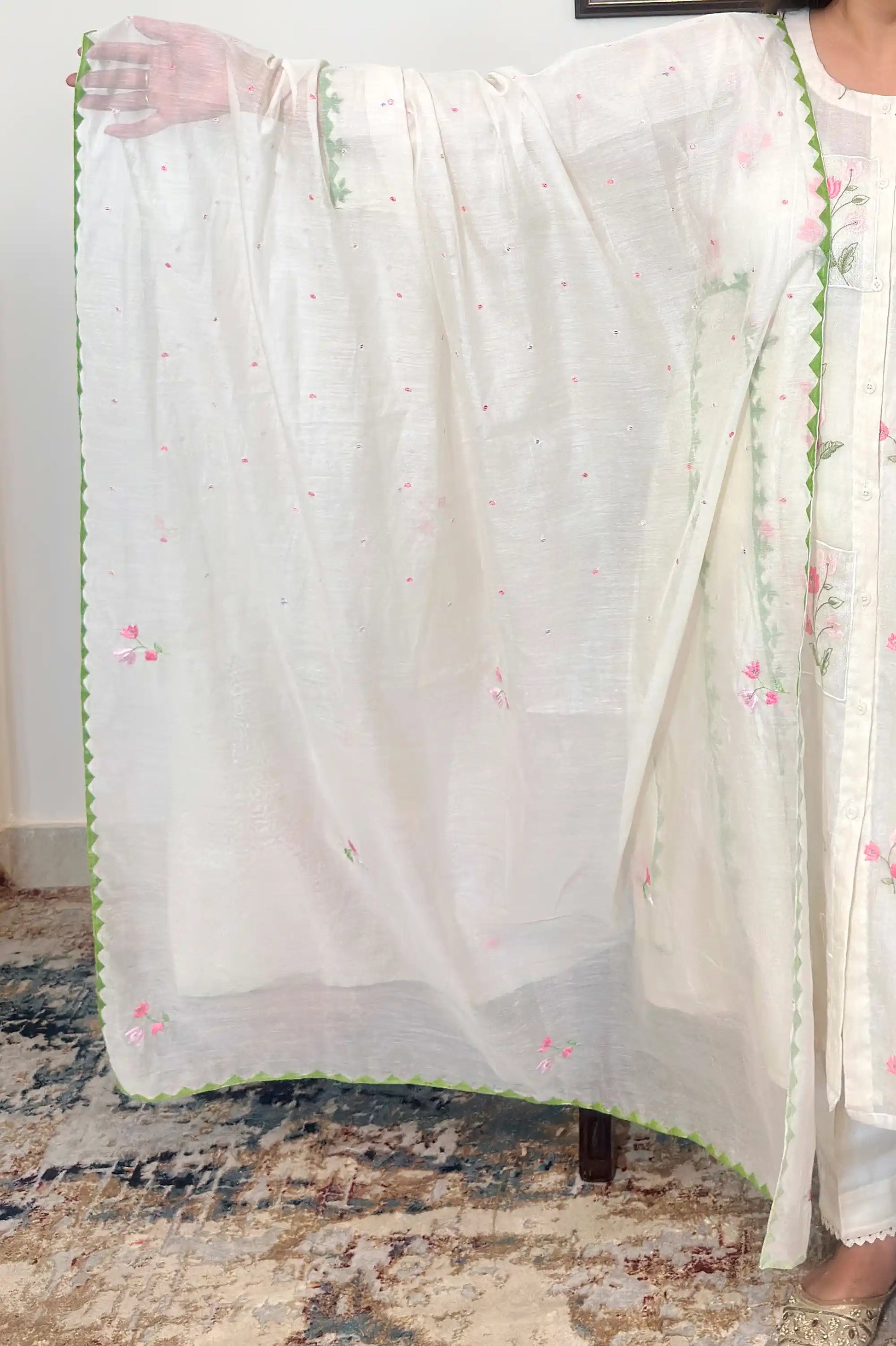 Close-up of the off-white chanderi dupatta with scattered pink embroidered motifs and a green scalloped applique border.