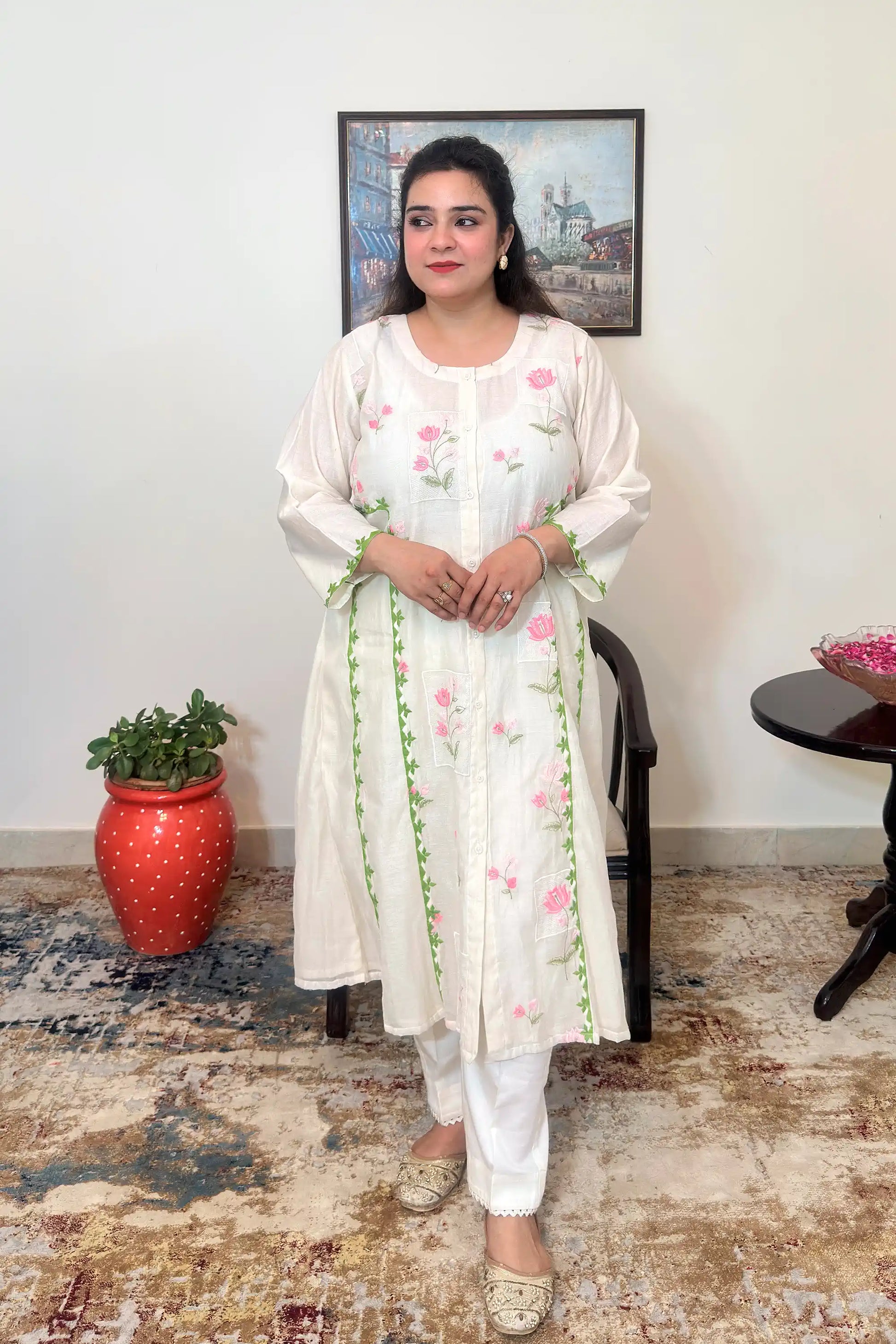 Front view of the off-white chanderi A-line kurta with pink floral embroidery and green applique vine, worn with off-white trousers, dupatta off.