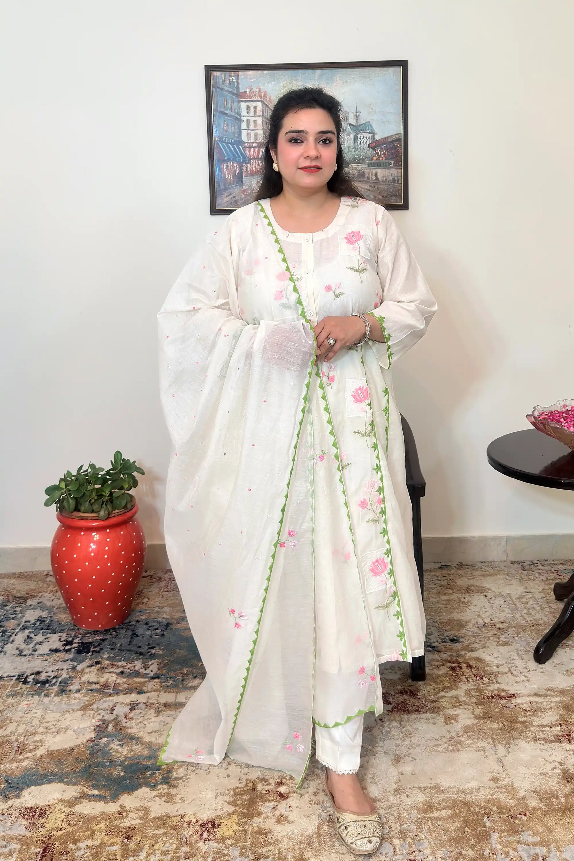 Front view of the off-white chanderi A-line kurta and dupatta with pink embroidery and green applique work, worn with off-white trousers, dupatta on.