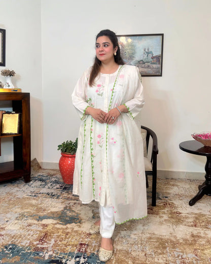 Front view of the off-white chanderi A-line kurta with pink floral embroidery and green applique vine, worn with off-white trousers, dupatta off.
