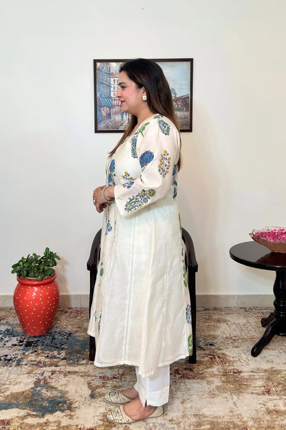 Side view of an off-white chanderi A-line kurta with blue-green floral mughal print and off-white trousers.