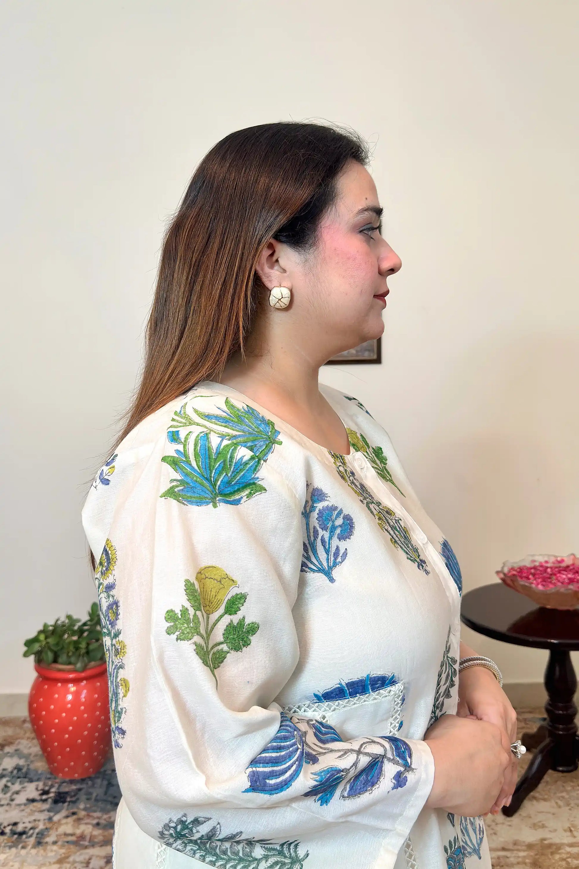 Close-up side view of the sleeve and button placket on an off-white chanderi kurta with blue-green floral hand print.