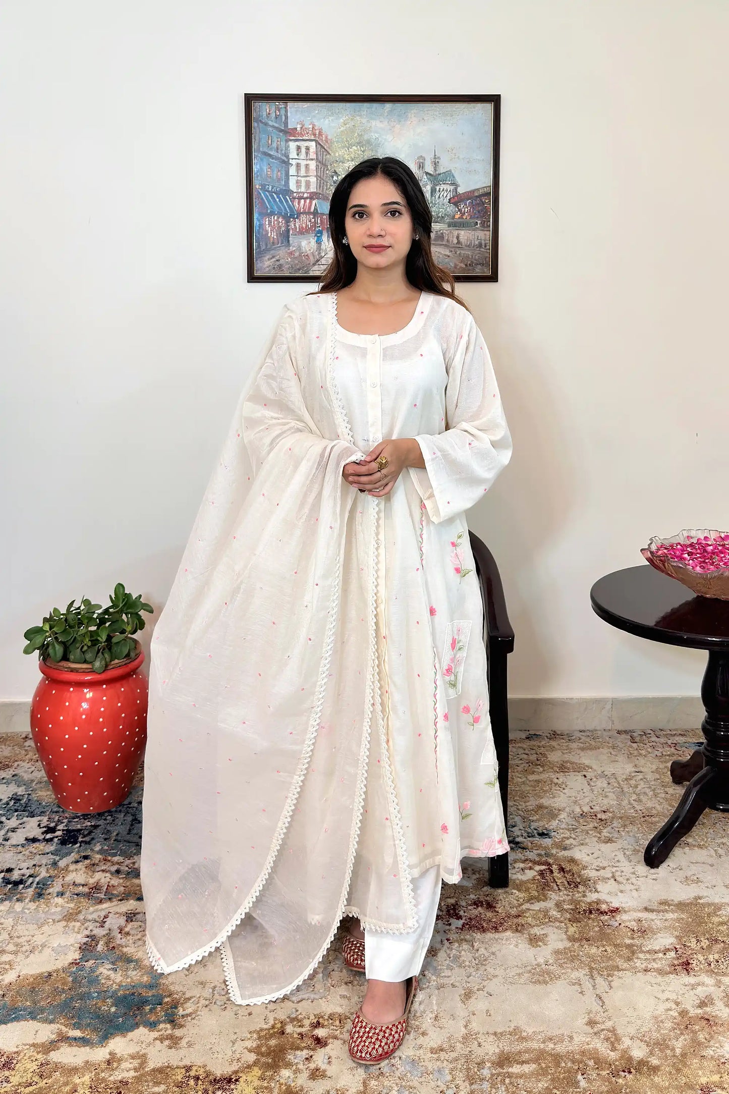 Front view of a woman wearing an off-white chanderi A-line kurta with pink resham floral embroidery, off-white trousers and off-white chanderi  dupatta with matching pink resham embroidery.