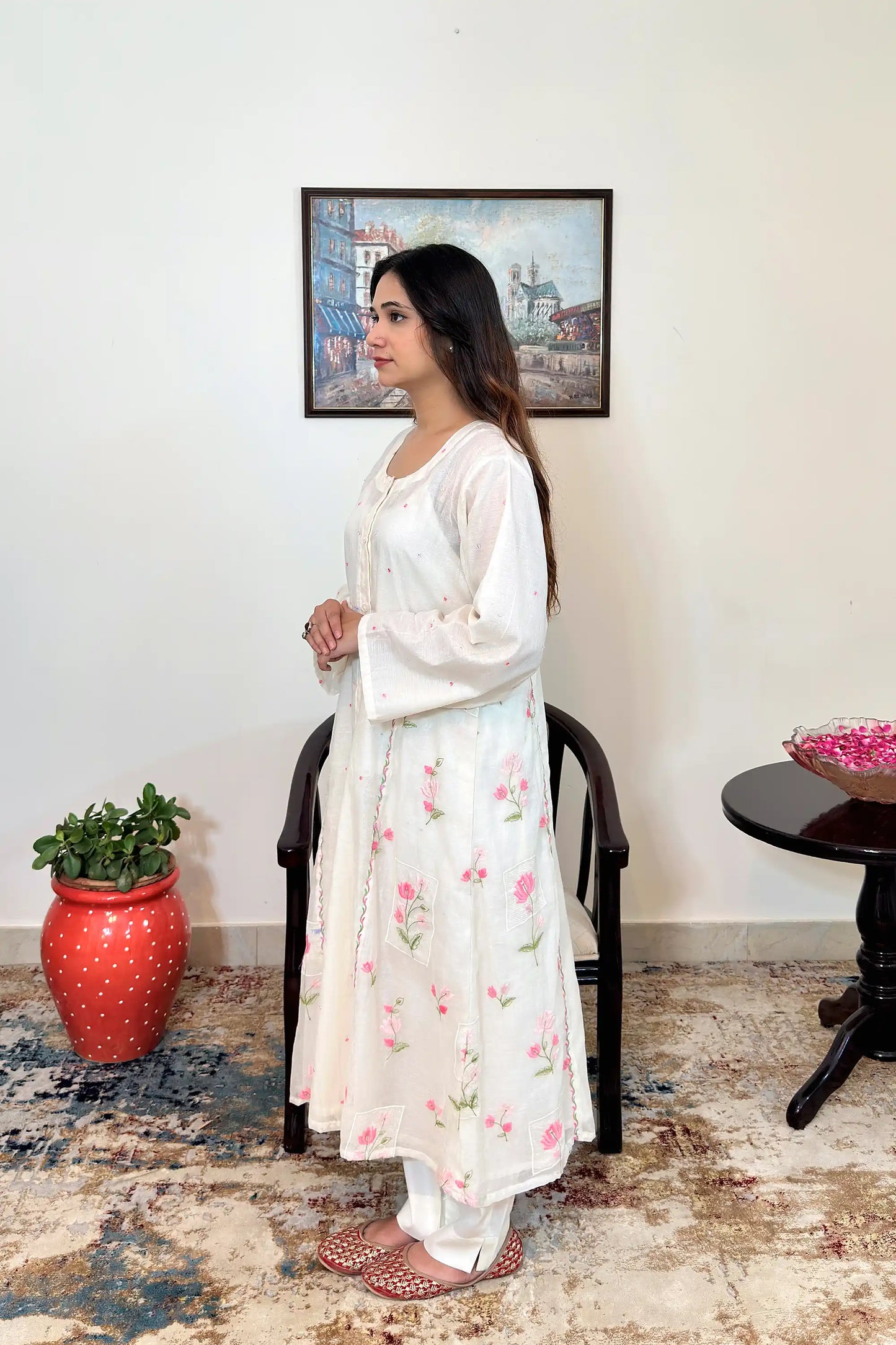 Side view of the off-white chanderi A-line kurta with pink resham floral embroidery and off-white trousers.