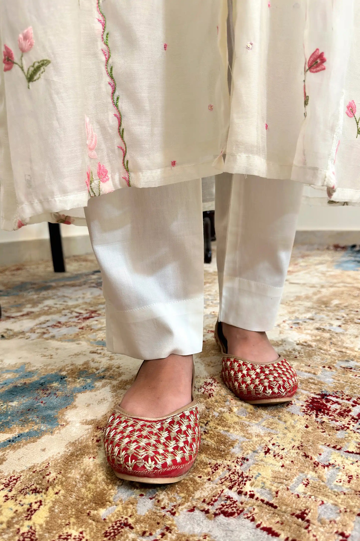 Close-up of the off-white trouser hems with pink resham embroidered kurta hem visible above.