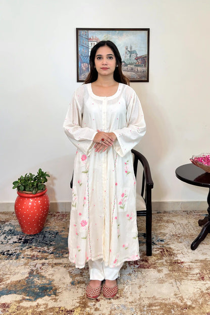 Front view of the off-white chanderi A-line kurta with pink resham floral embroidery and off-white trousers.
