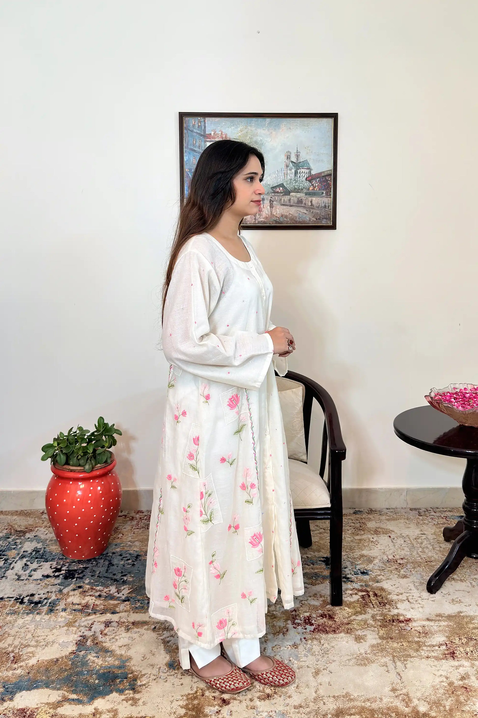 Side view of the off-white chanderi A-line kurta with pink resham floral embroidery and off-white trousers.