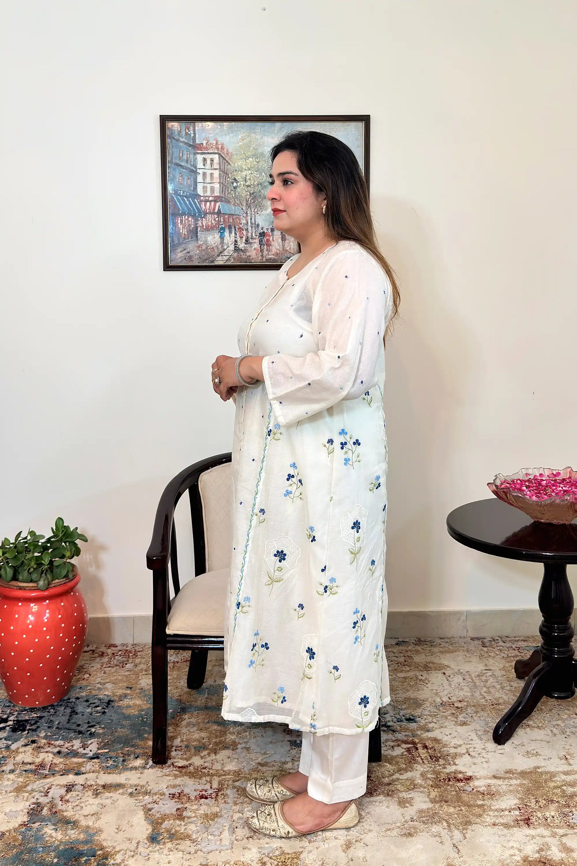 Side view of an off-white chanderi A-line kurta with dupatta off, showing blue floral resham embroidery along the front and back panel, paired with off-white trousers.