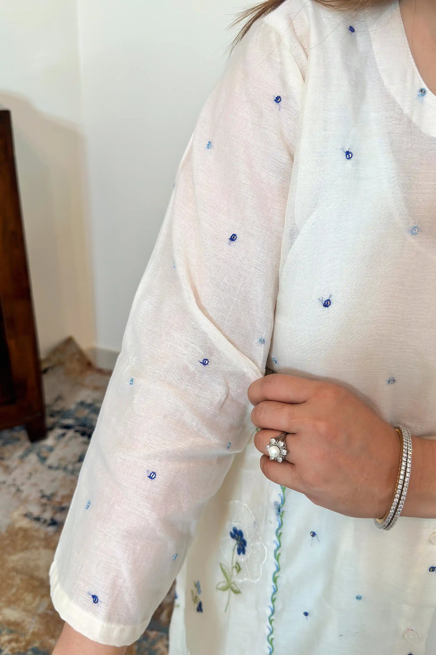 Close-up of the sleeve of an off-white chanderi kurta with scattered blue resham embroidery.