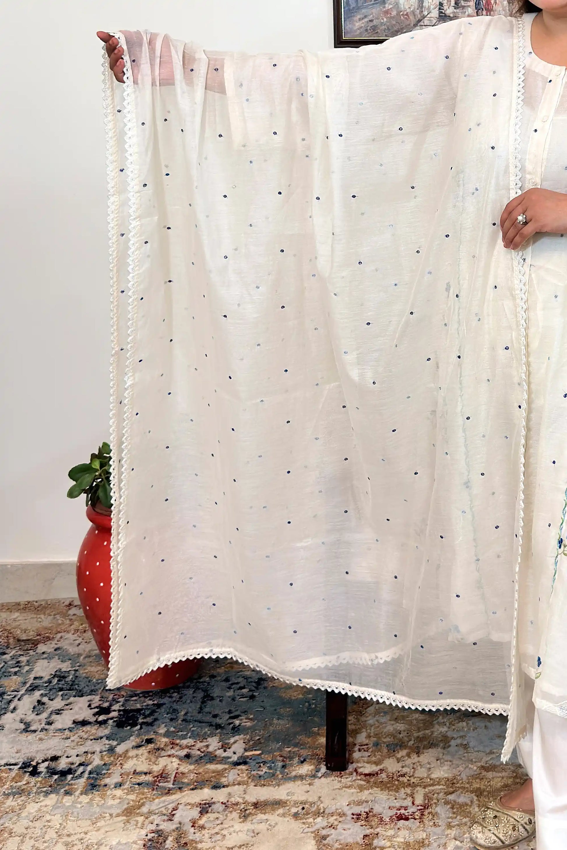 Close-up of an off-white chanderi dupatta with scattered blue resham embroidery and a scalloped lace edge.
